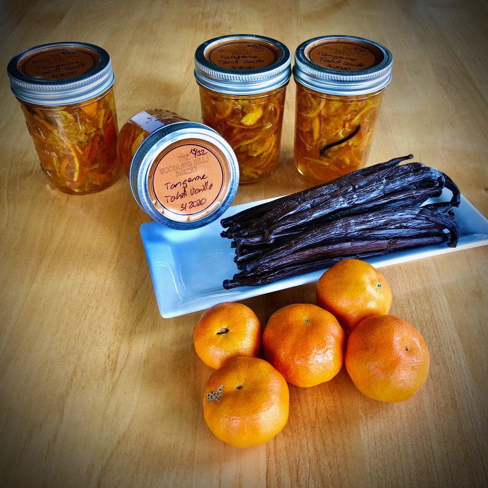 Home-canned tangerine and Tahitian vanilla marmalade in labeled jars beside vanilla beans and tangerines