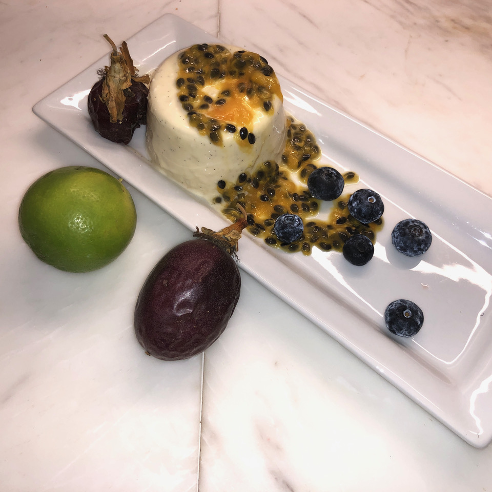 Plated vanilla bean custard with passion fruit sauce, lime, and blueberries
