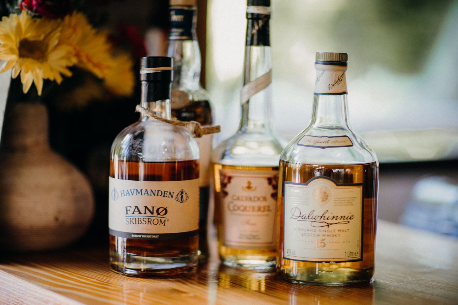 Bottles of rum, calvados brandy, and whisky on a rustic wooden table