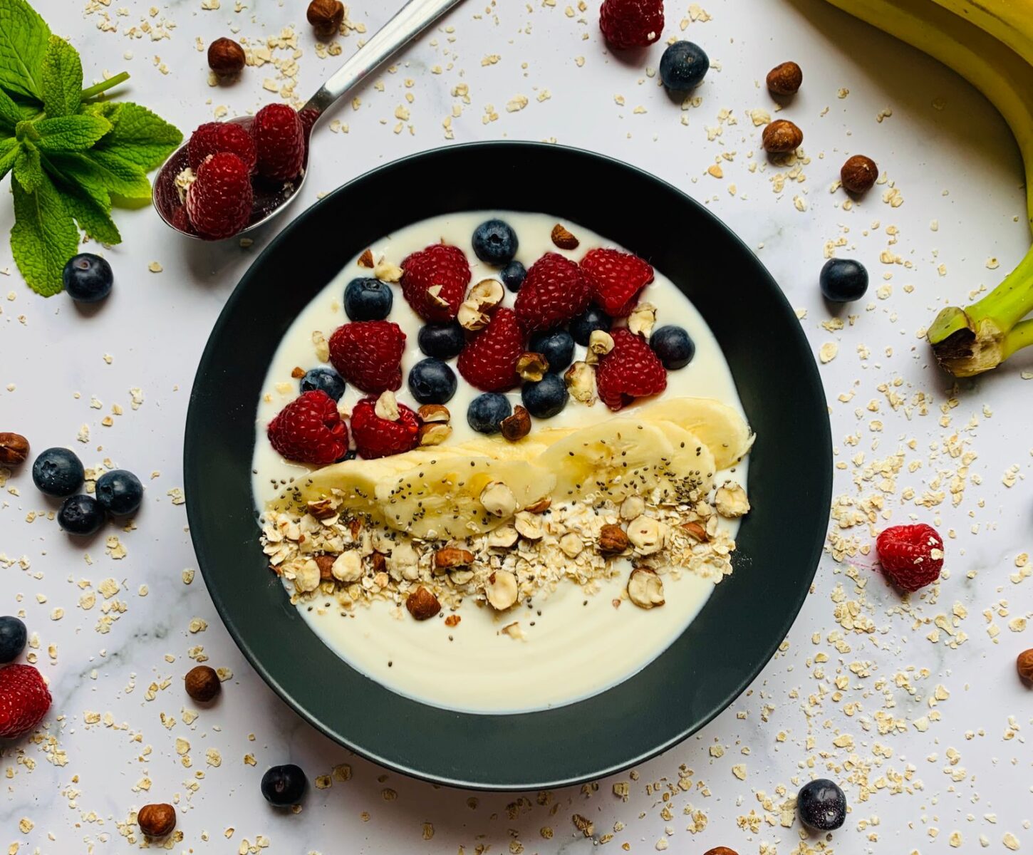 Healthy yogurt breakfast bowl with raspberries, blueberries, banana and oats